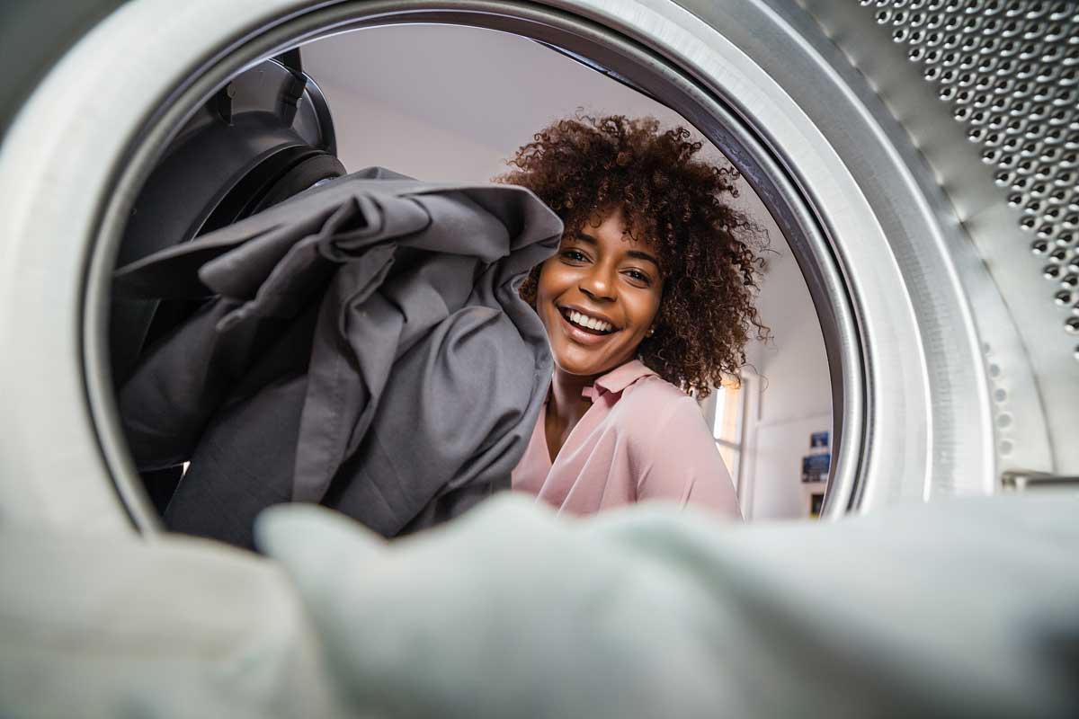 Young black African American woman holding a basket of clothes to be washed in a automatic laundry