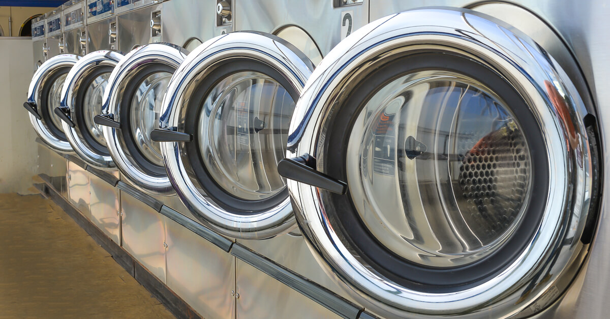 Row of industrial laundry machines in laundromat commercial laundry service.